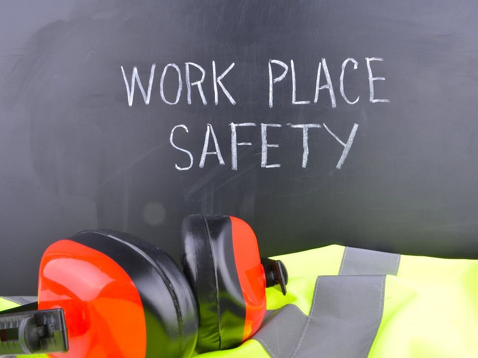 hearing protection and safety vest in front of blackboard